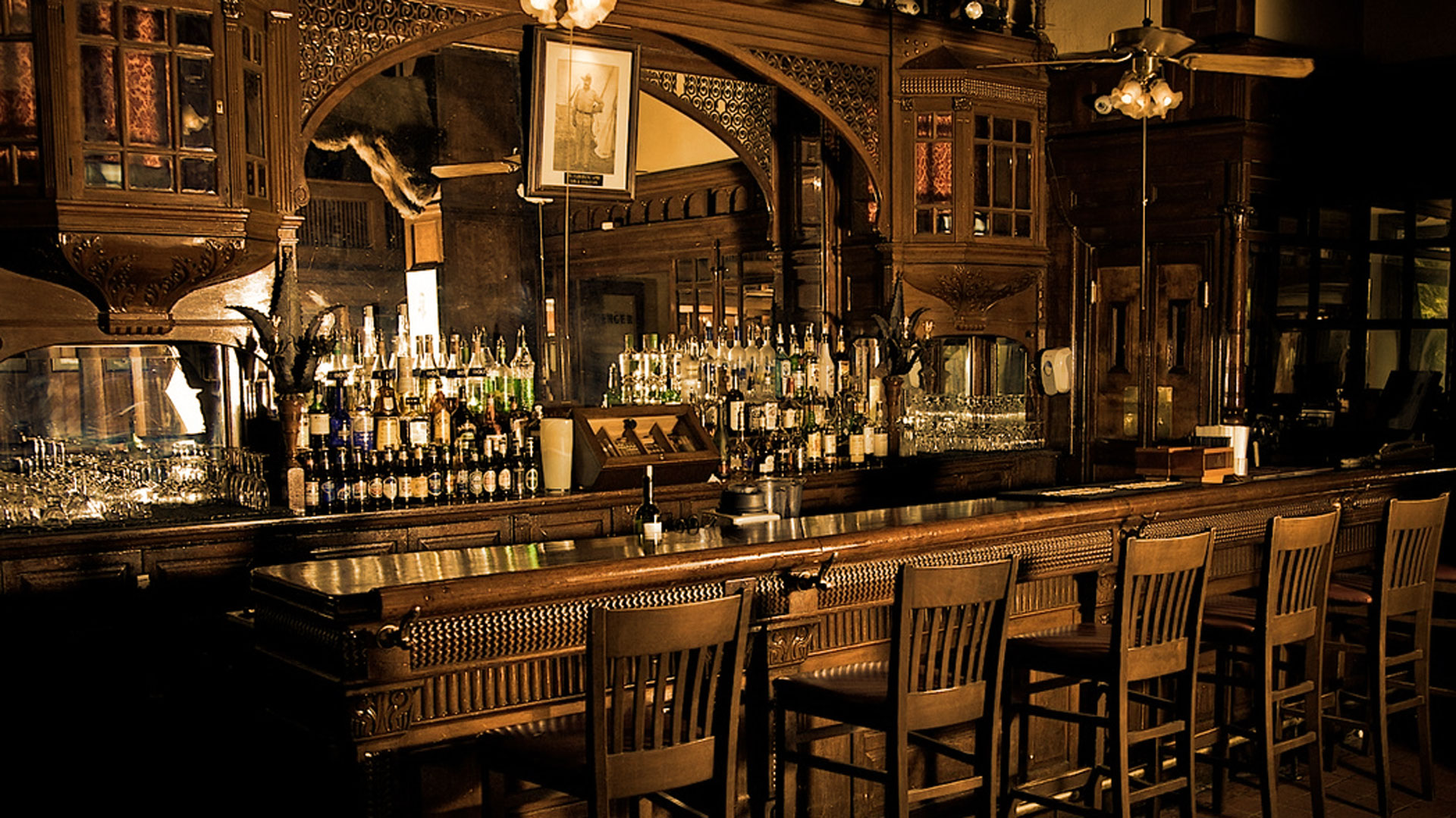 A bar with many bottles of alcohol on the counter.