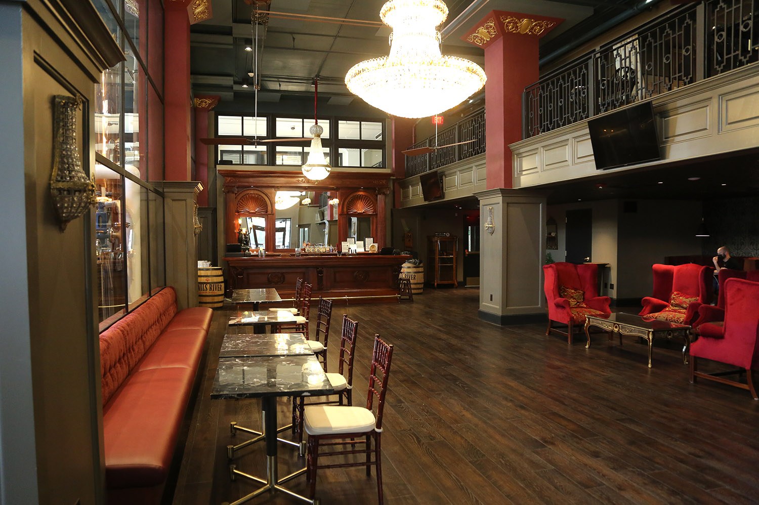 A restaurant with wooden floors and red chairs.